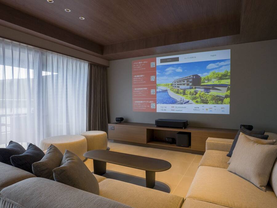 A modern living room with a large flat-screen TV mounted on the wall, a sofa, a coffee table, and a side table.