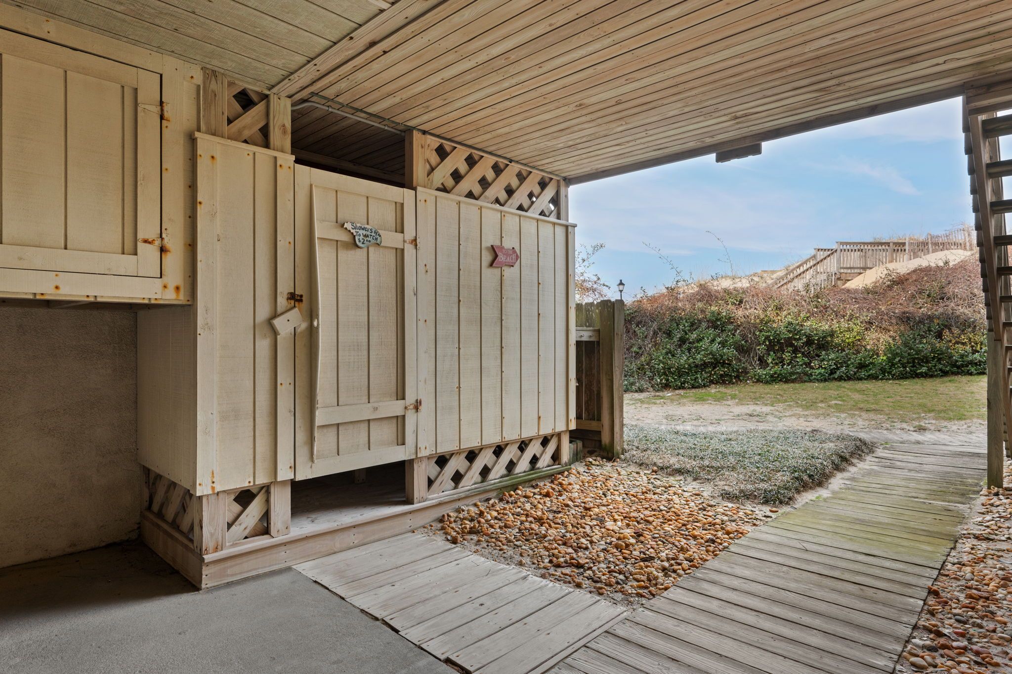 A wooden structure with a door, a sign indicating a beach view, and a pathway leading to a beach.