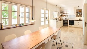 Eine moderne Küche mit weißen Schränken, einem Holzespeise-Tisch und Pendelleuchten.