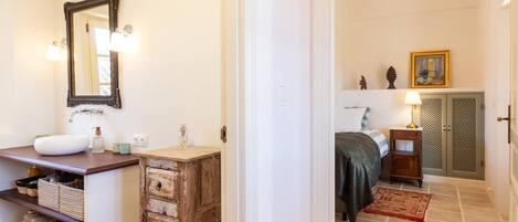 Un baño con lavamanos blanco, espejo y mueble de madera con cajones.