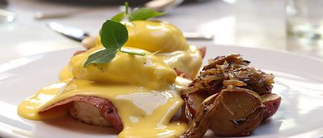 A plate of food with eggs benedict and roasted potatoes.
