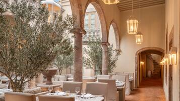 A restaurant with outdoor seating, stone columns, and hanging lanterns.