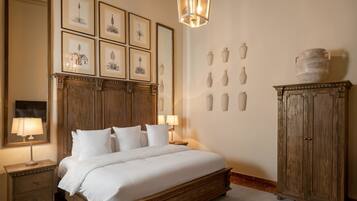 Une chambre à coucher avec un lit en bois, des tables de chevet avec des lampes, des reproductions botaniques encadrées accrochées au mur et une commode avec des vases.