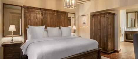 A bedroom with a large wooden bed, wooden wardrobe, and a chandelier.