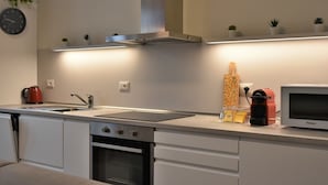 Een moderne keuken met een inbouwoven, een magnetron, een waterkoker en een plankje met kleine planten.