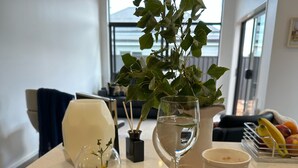 Un plateau de petit-déjeuner avec des œufs brouillés, un croissant, des myrtilles et une pêche, posé sur une table dans une cuisine moderne dotée d’une grande fenêtre et d’une plante en pot.