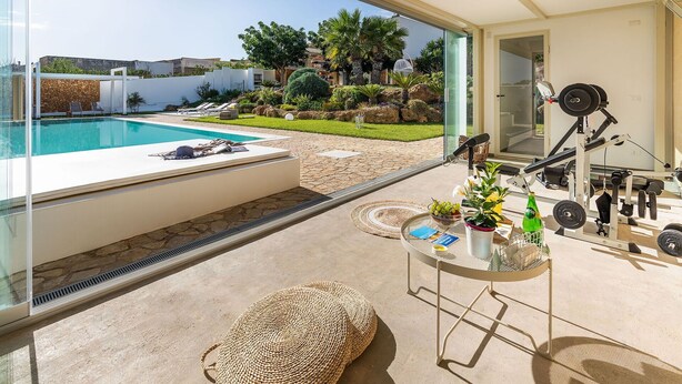 A modern outdoor area with a swimming pool, exercise equipment, and a dining table with outdoor seating. - Beautiful private villa for 10 guests with WIFI, A/C, private pool, TV and terrace (Trapani)