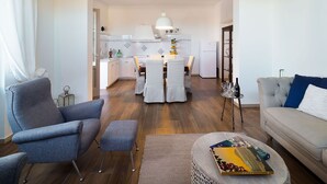 A modern living room with a grey sofa, a coffee table with books, and a dining area with a white table and chairs. - Beautiful private villa for 10 guests with WIFI, A/C, private pool, TV and terrace (Trapani)