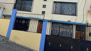A multi-story building with a blue and beige facade, featuring a gated entrance with decorative metalwork. - Very private and quiet suite with a panoramic view of the entire city.  (Quito)