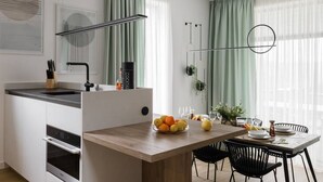 A modern kitchen with a wooden island, white cabinetry, and a dining area with black chairs.
