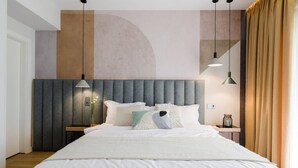 A modern bedroom with a large bed, a headboard with vertical panels, bedside lamps, and a nightstand with a vase.