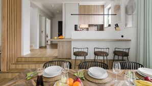 A modern kitchen with a central island, bar stools, and a dining table set for four.