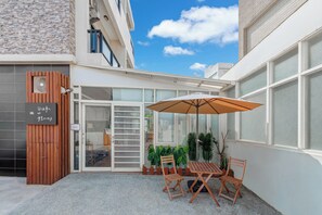 Eine Terrasse mit Tisch und Stühlen, eine Holztür und eine Glastür, die zu einem Innenbereich führen.