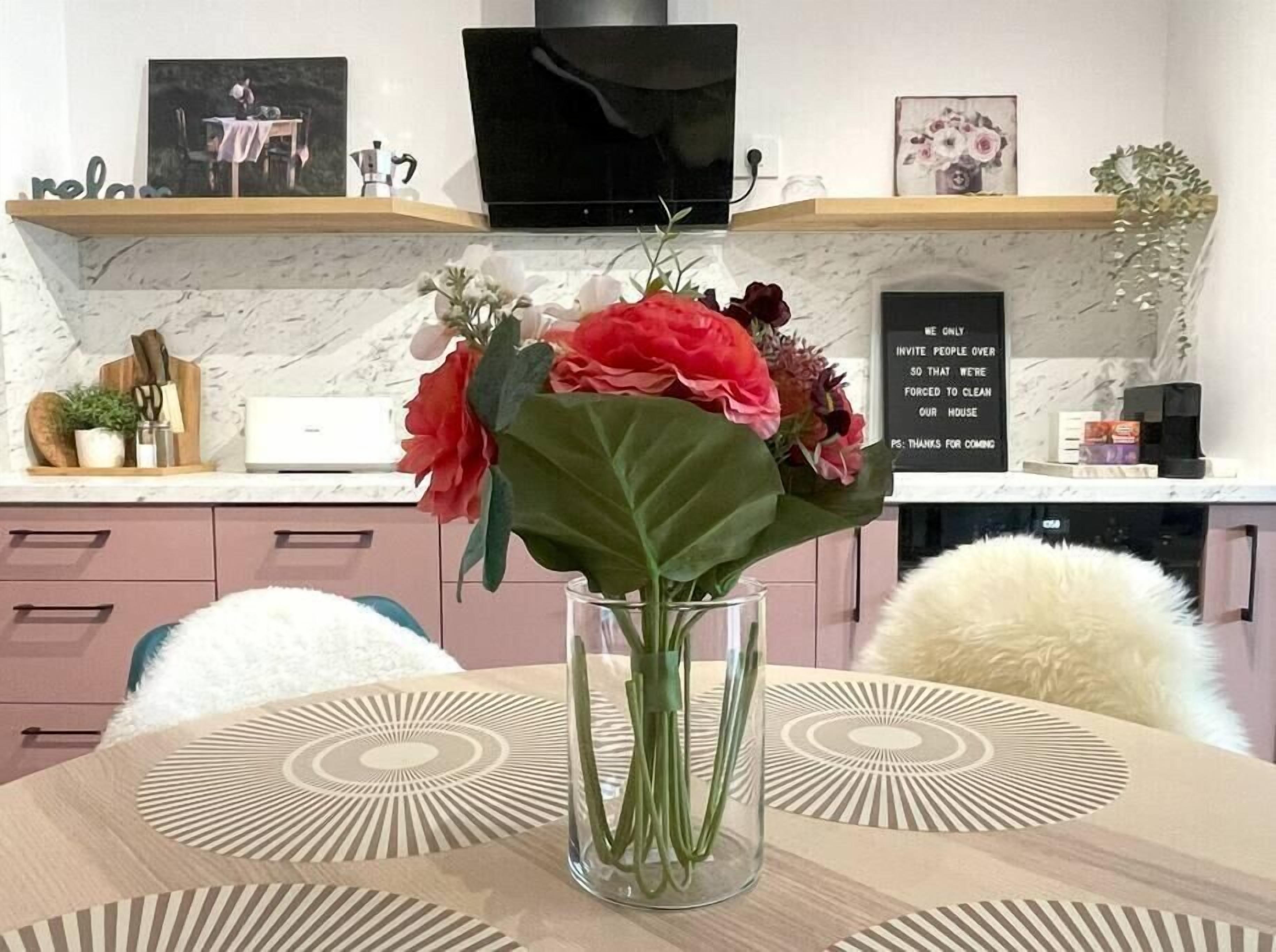 A dining table with a vase of flowers, a television above, and a sign on the wall.