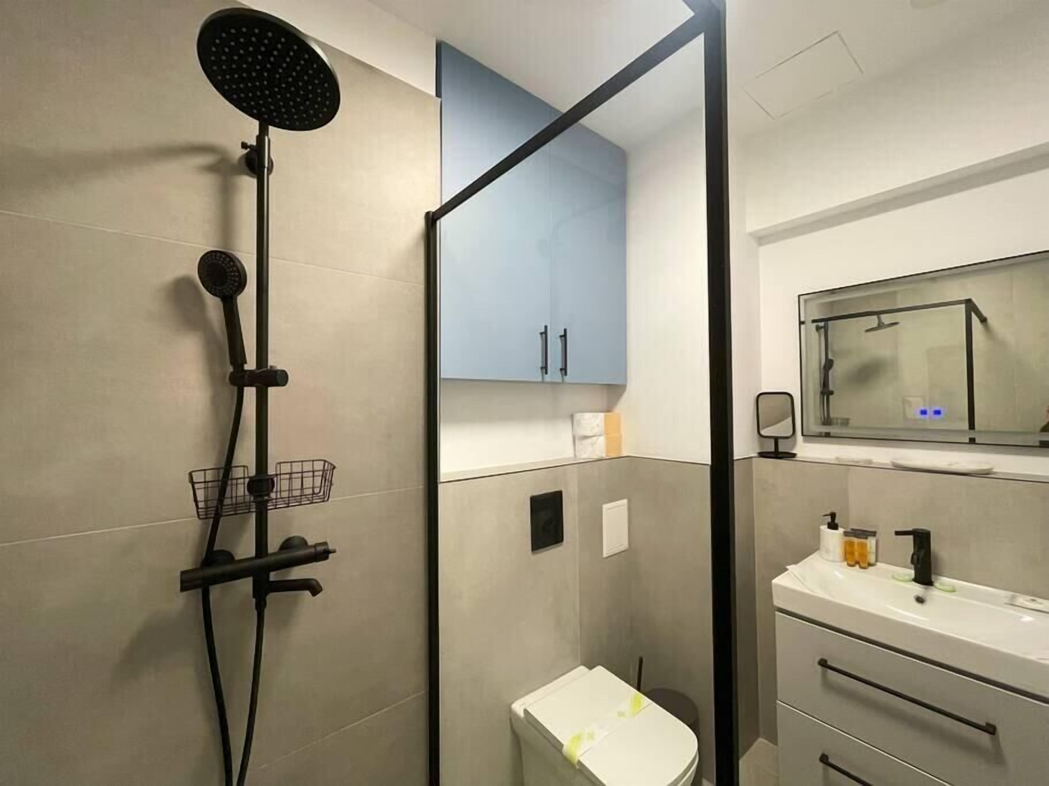 A modern bathroom with a shower, toilet, and sink.