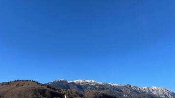 A mountain range with snow-capped peaks in the background and a town with buildings in the foreground.