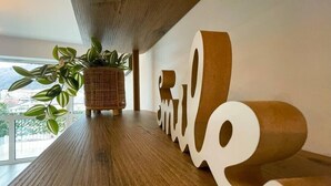 En receptionsdisk i trä med en krukväxt och en stor, stiliserad skylt med texten ”Le”.