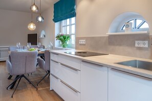 Una cucina moderna con una grande isola, mobili bianchi e lampade a sospensione.