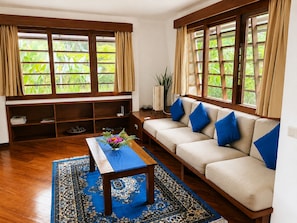 A living room with a sofa, a coffee table, and a bookshelf. - The Ikat Villa (Ubud)