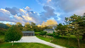 A rural landscape with a gravel driveway leading to a wooden barn and a house. - Madaket Farmhouse- Walk to Beach and Sunsets- Near Bike Path -Nantucket (Nantucket)