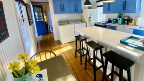 A kitchen with blue cabinets, a white island with stools, a stove, a microwave, and a sink. - Madaket Farmhouse- Walk to Beach and Sunsets- Near Bike Path -Nantucket (Nantucket)