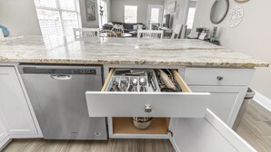A kitchen with a built-in dishwasher, a marble countertop, and a drawer organizer with utensils. - Cozy Hideaway! Spacious and centrally located. Pet Friendly! (Pensacola)