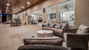 A spacious indoor area with a high ceiling, large windows, and a mix of seating arrangements including a sofa and chairs. - Pecan Valley Resort| BRAND NEW Private Pool and Hot Tub w/ Slide (Hurricane)