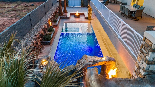 A swimming pool with a stone border and a fire feature.