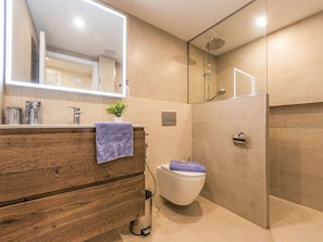 Une salle de bain moderne avec un meuble-lavabo en bois, des toilettes, un espace douche et un grand miroir.