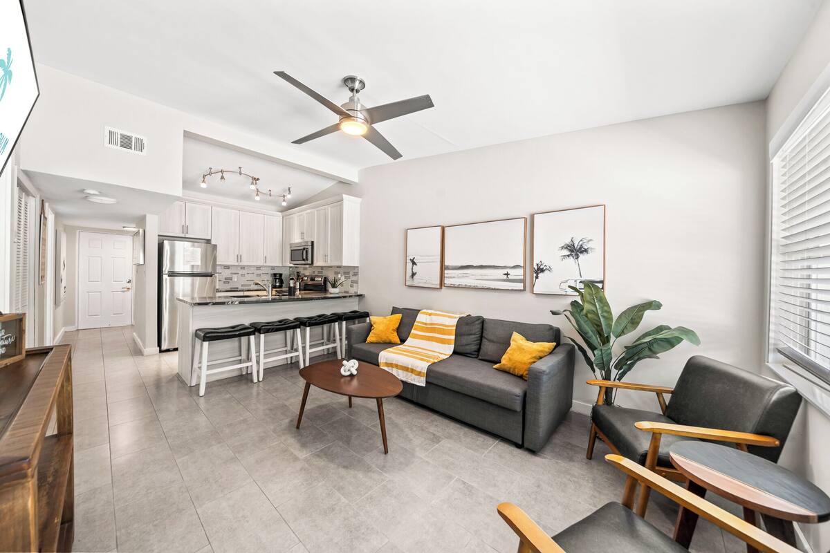A modern living room with a gray sofa, wooden coffee table, and a ceiling fan.