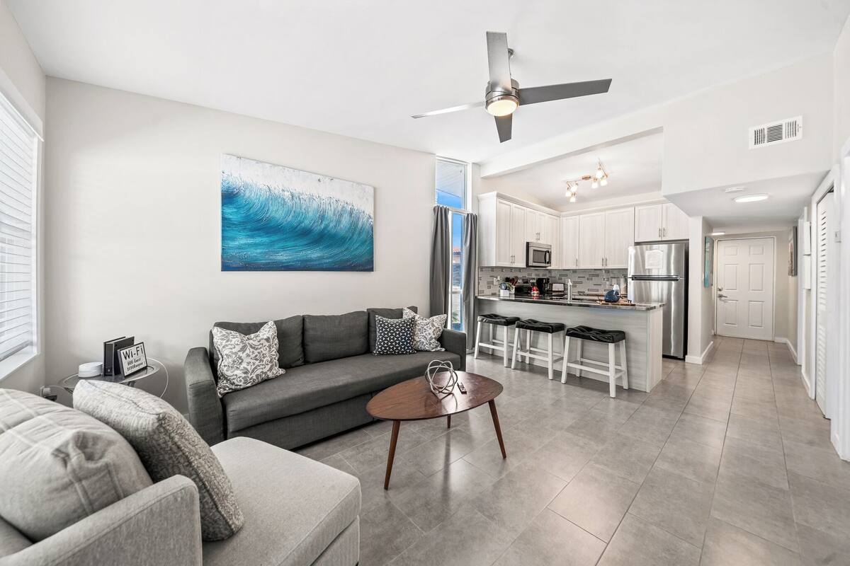 A modern living room with a gray sofa, a coffee table, and a ceiling fan.