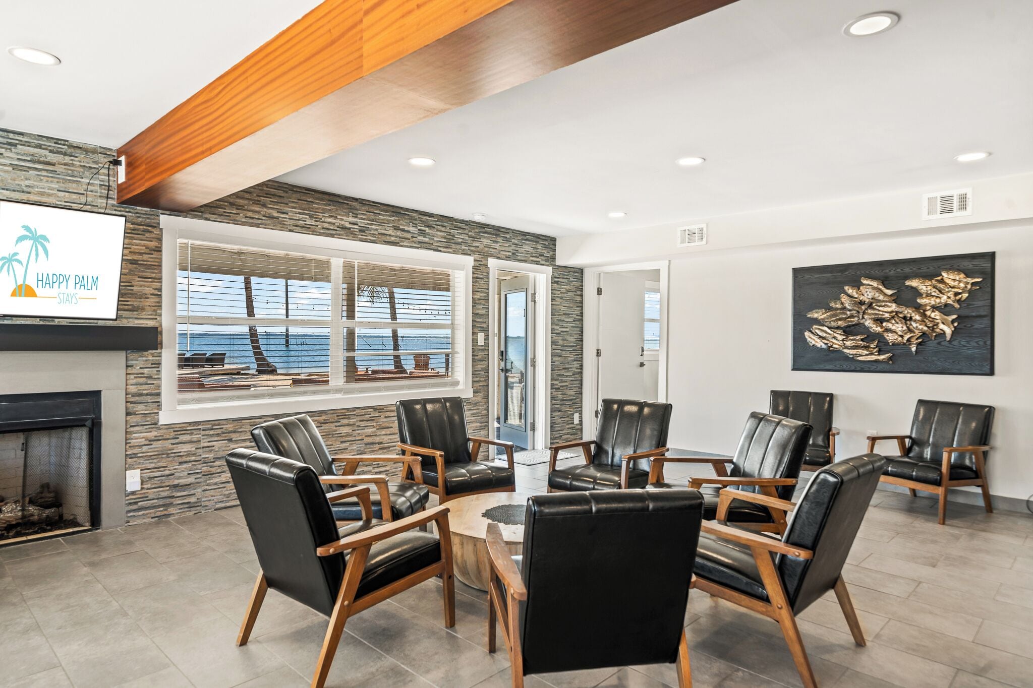 A spacious lobby with a fireplace, comfortable leather chairs, a coffee table, and a large window offering a view of the ocean.