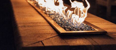 A row of flames on a long table, with string lights in the background.