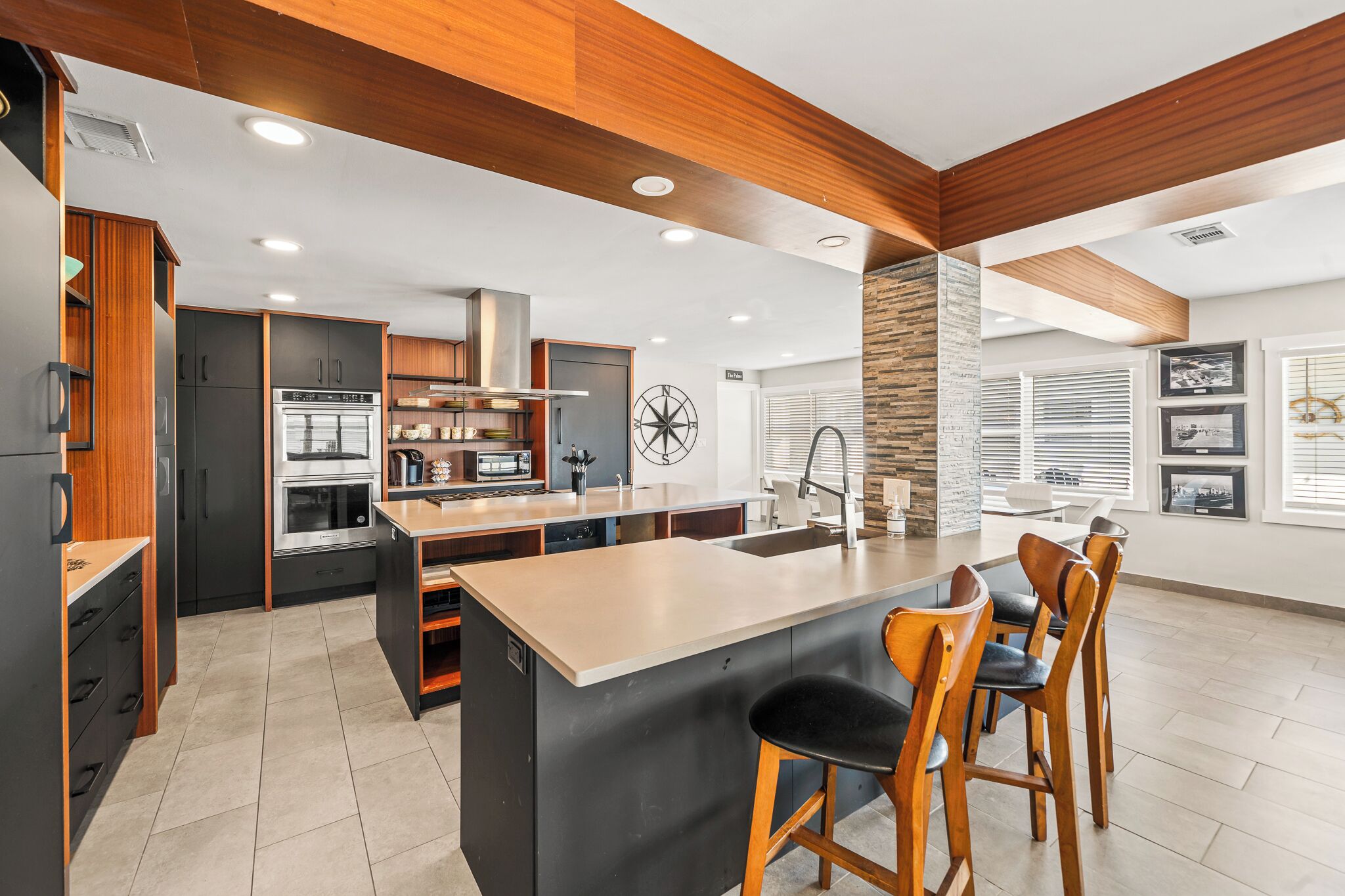 A modern kitchen with a central island, built-in appliances, and wooden accents.