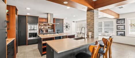 A modern kitchen with a central island, built-in appliances, and wooden accents.