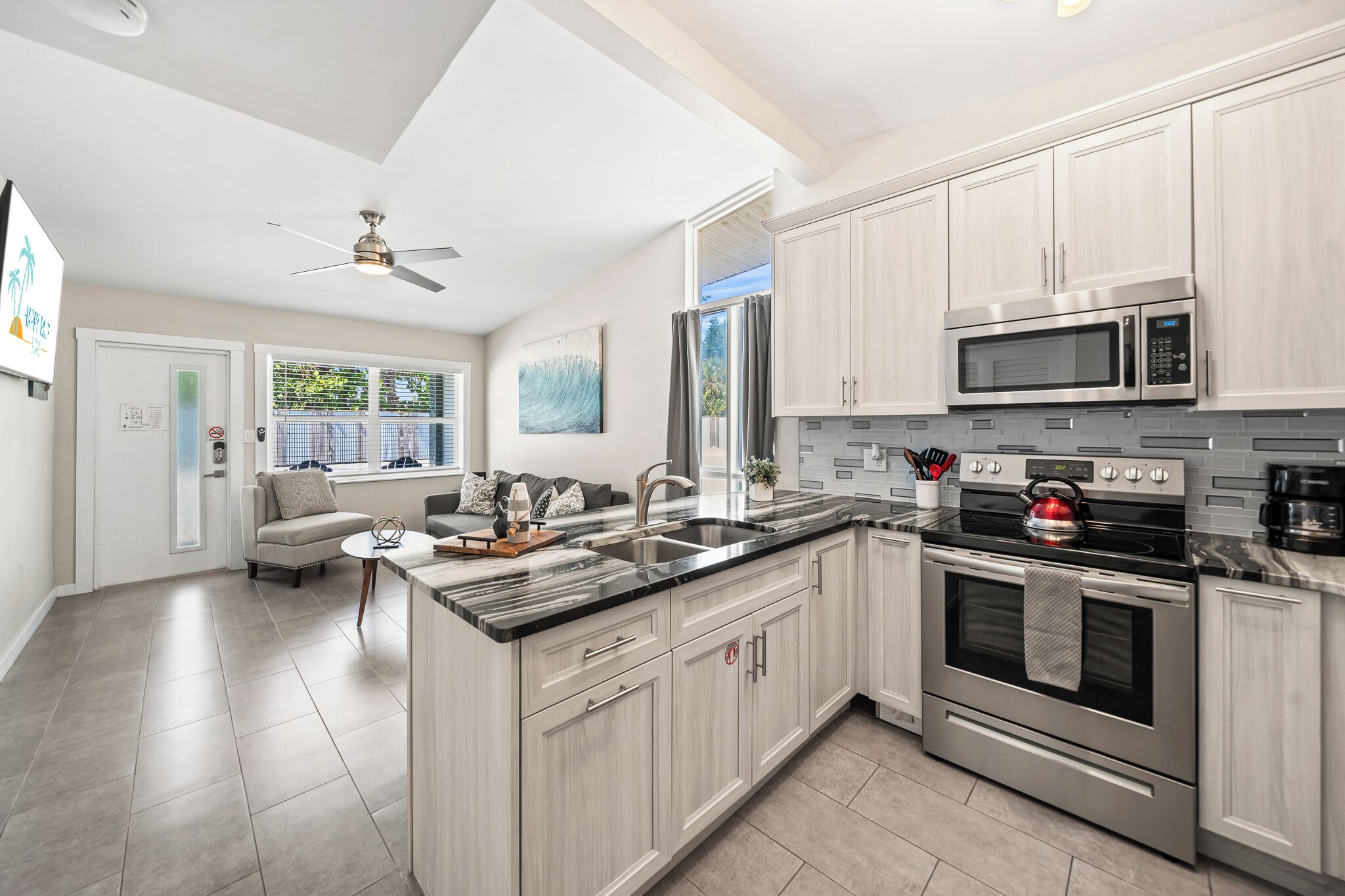 A modern kitchen with a large island, stainless steel appliances, and light wood cabinetry.