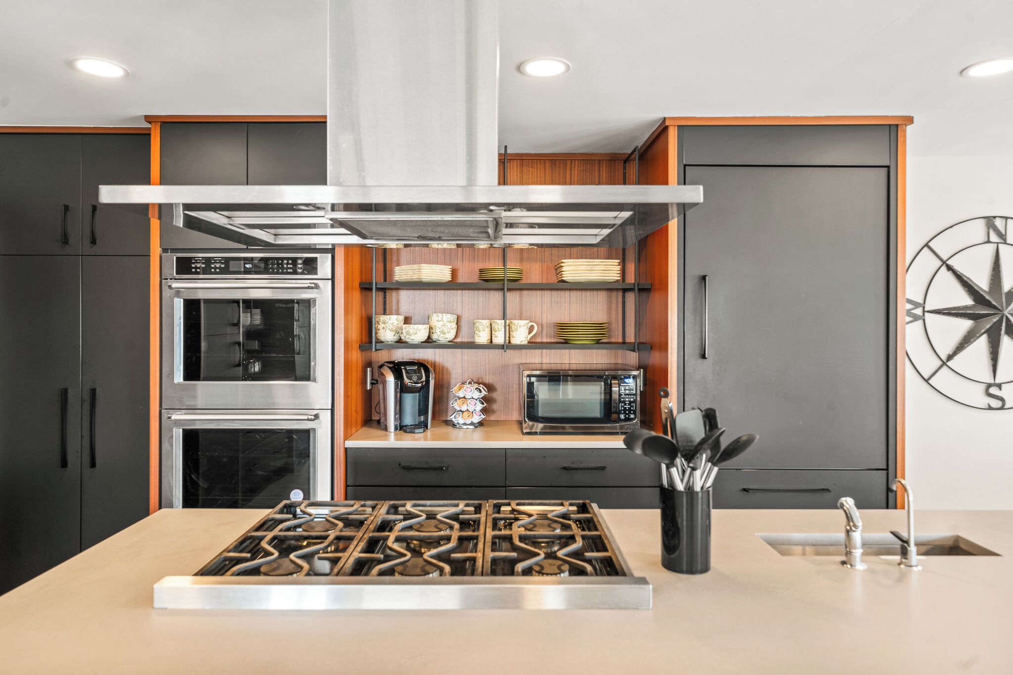 A modern kitchen with a built-in oven, microwave, and gas stove.