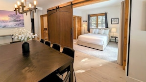 Un dormitorio moderno con una cama grande, un armario de madera y una zona de comedor con mesa y sillas.