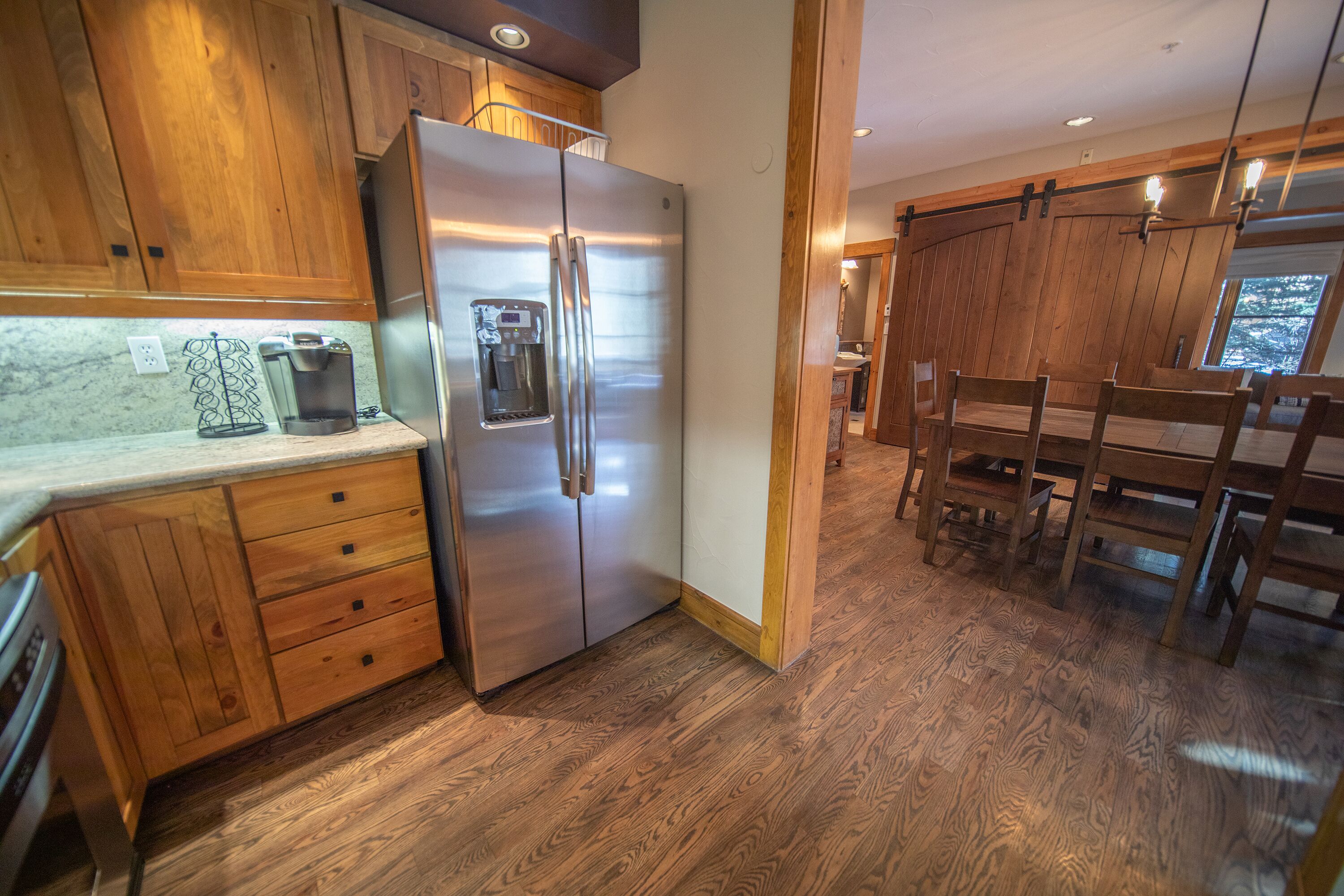 A kitchen with wooden cabinets, a stainless steel refrigerator, and a coffee maker on the counter.