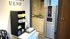 A kitchenette with a stainless steel refrigerator, a shelf with dishes, and a wall sign reading "CHAAAN UENO". - CHA-AN UENO (Tokyo)