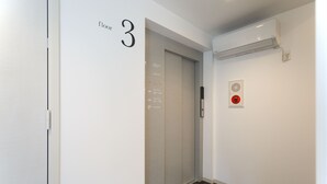 A hallway with a door labeled '3' and a fire alarm on the wall. - CHA-AN UENO (Tokyo)
