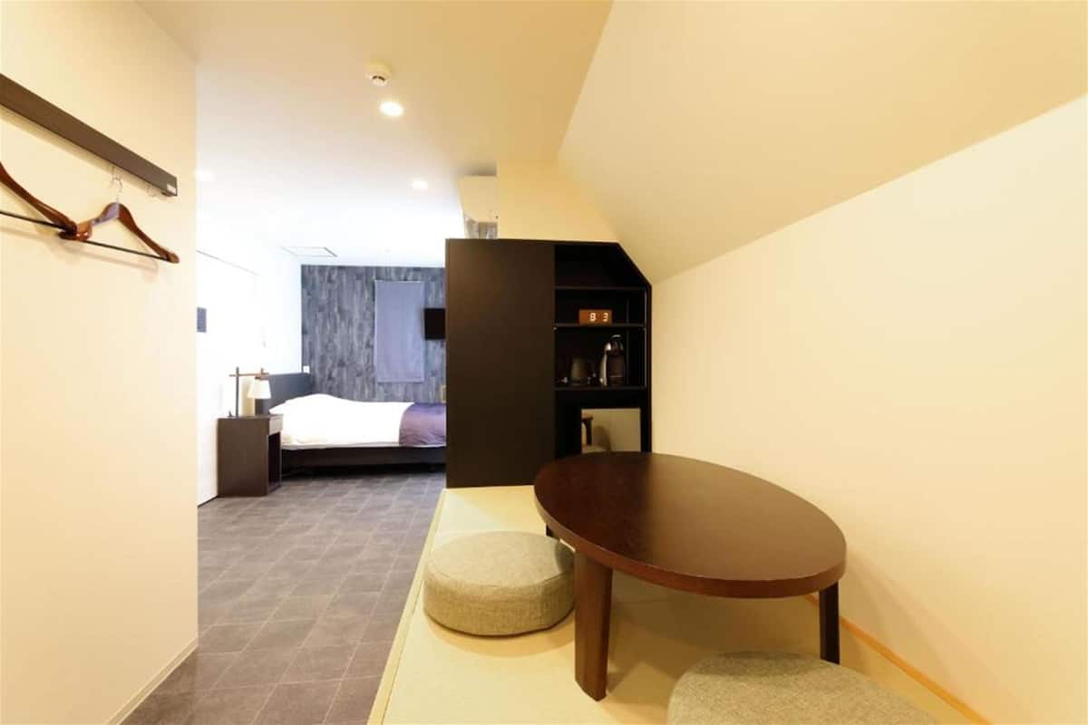 Une chambre d’hôtel avec un lit, une petite table et une bibliothèque.