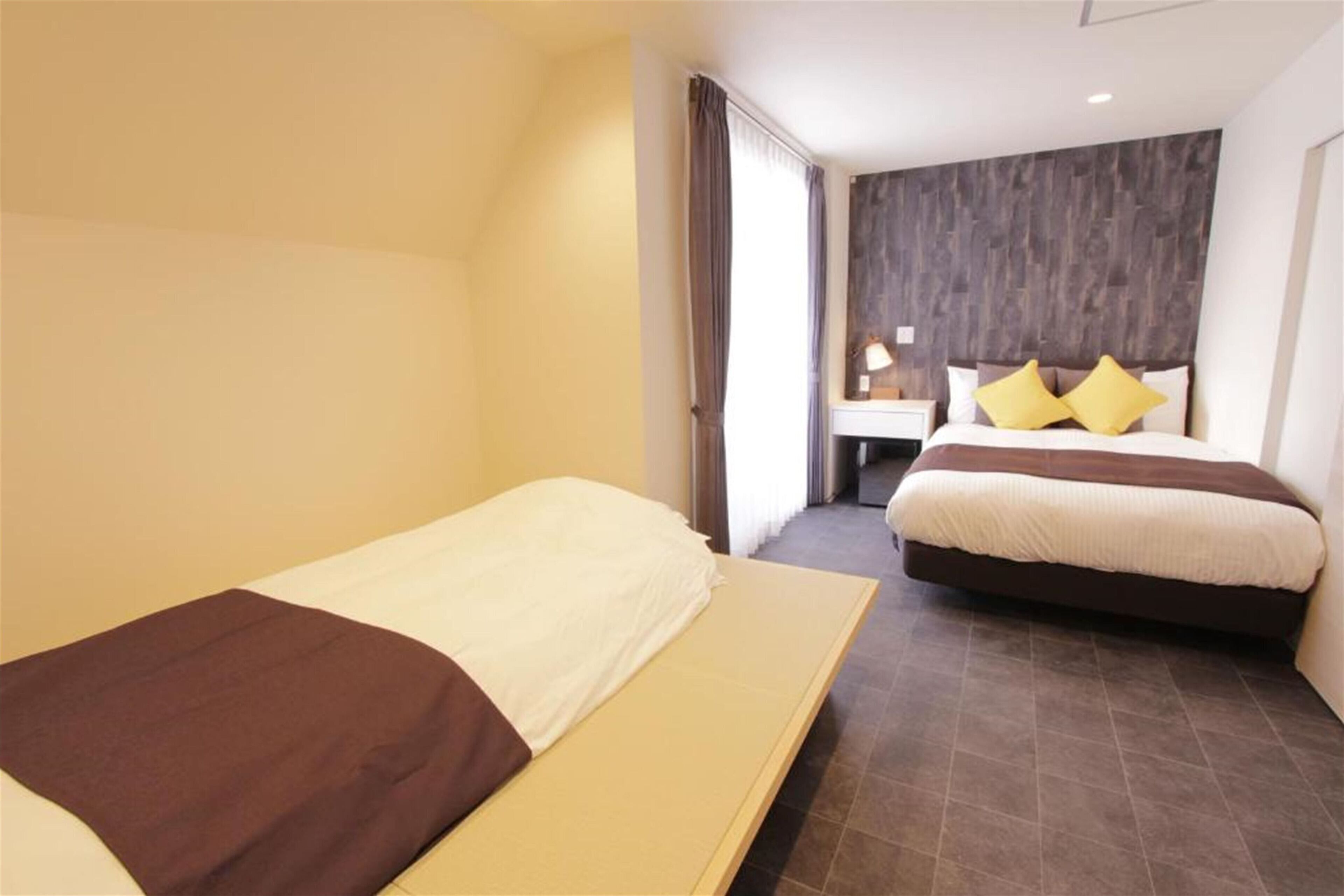 Une chambre d’hôtel avec deux lits, une table de chevet et une lampe.