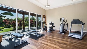 Un gimnasio amplio en casa con cinta de correr, elíptica y banco de pesas.