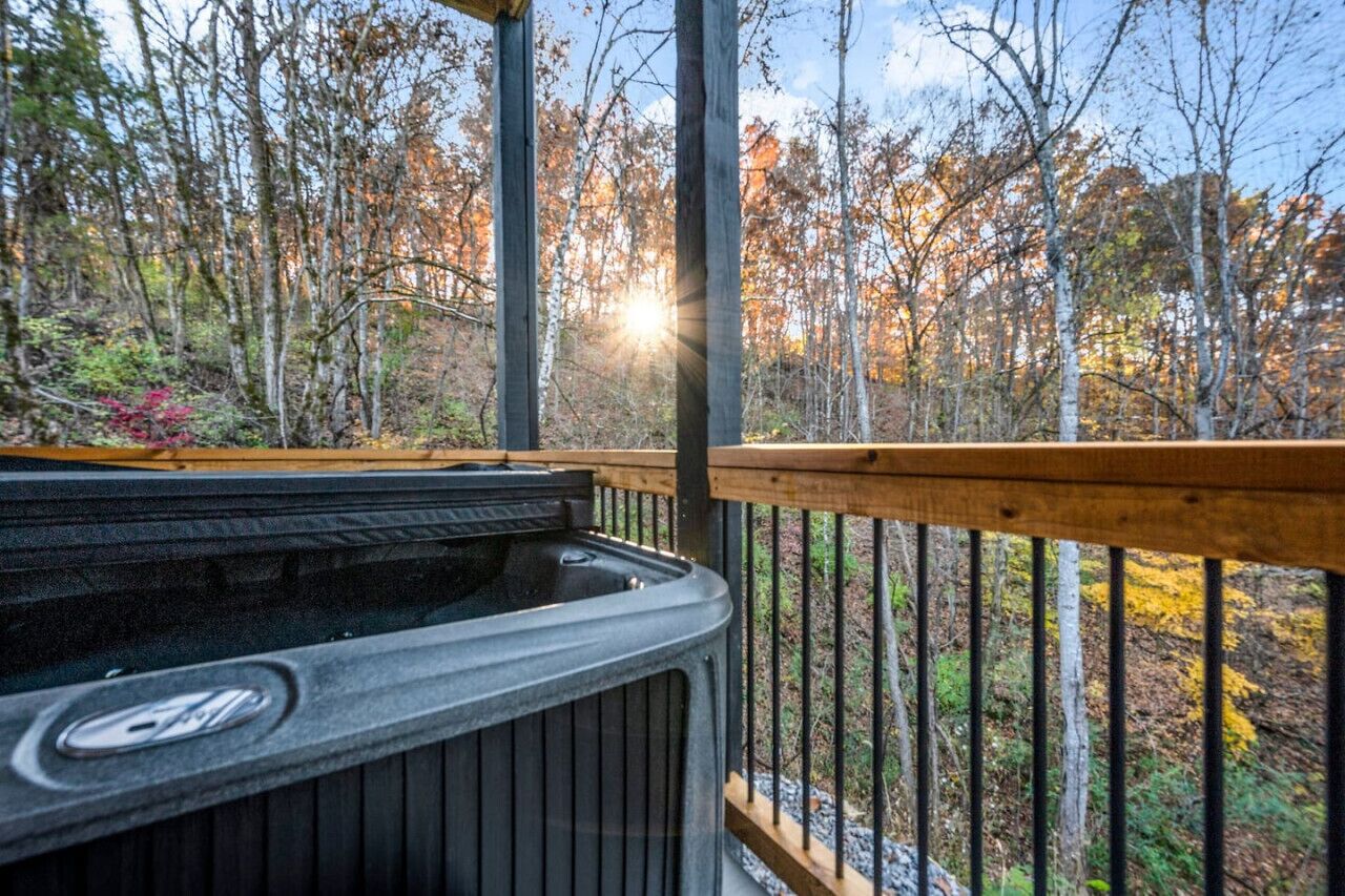 Un bain à remous sur une terrasse en bois, avec vue sur une forêt.