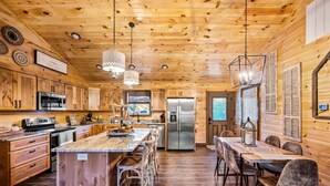 L’intérieur d’un chalet en bois comprend une cuisine, un coin repas et un grand îlot central doté de tabourets de bar.