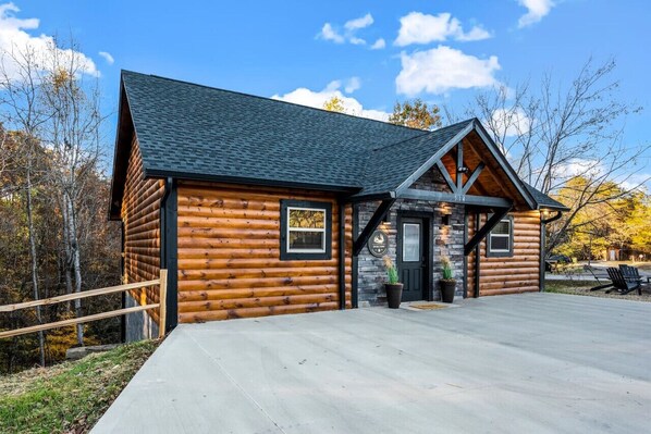 A log cabin with a stone foundation, a dark roof, and a wooden exterior.
