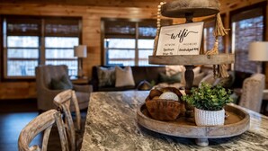 Un intérieur en bois avec une table ronde sur laquelle on aperçoit un panneau, un bol rempli de noix et une plante en pot.