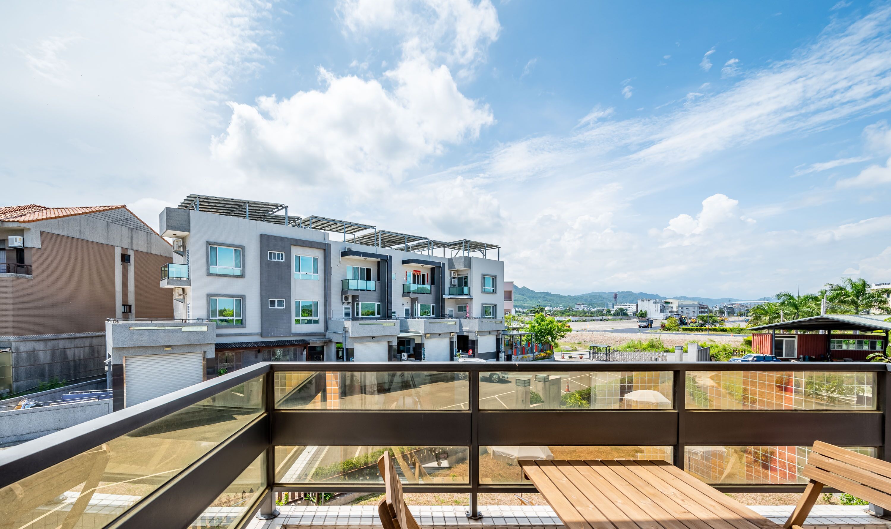 Ein modernes Mehrstöckengebäude mit großen Fenstern und einem Balkon mit Holzmöbeln.