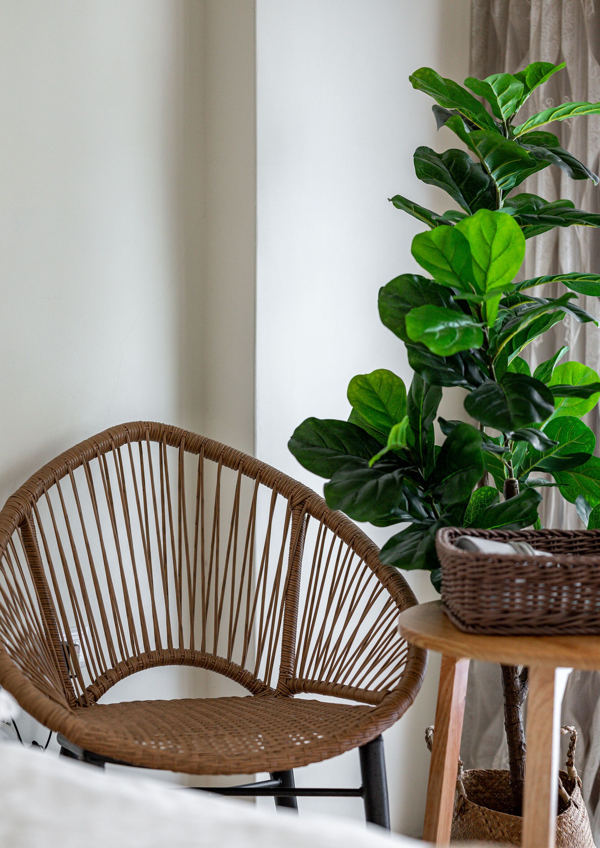 A wicker chair, a potted plant, and a small table with a basket.